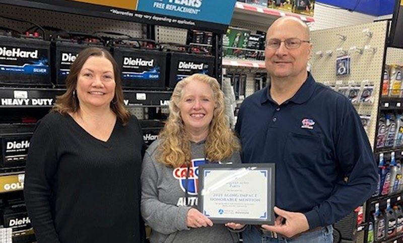 Two women and one man holding certificate.