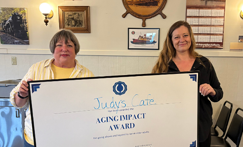 Two woman holding oversized certificate.