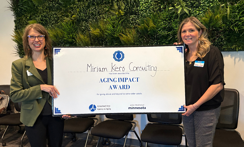 Two woman holding oversized certificate.