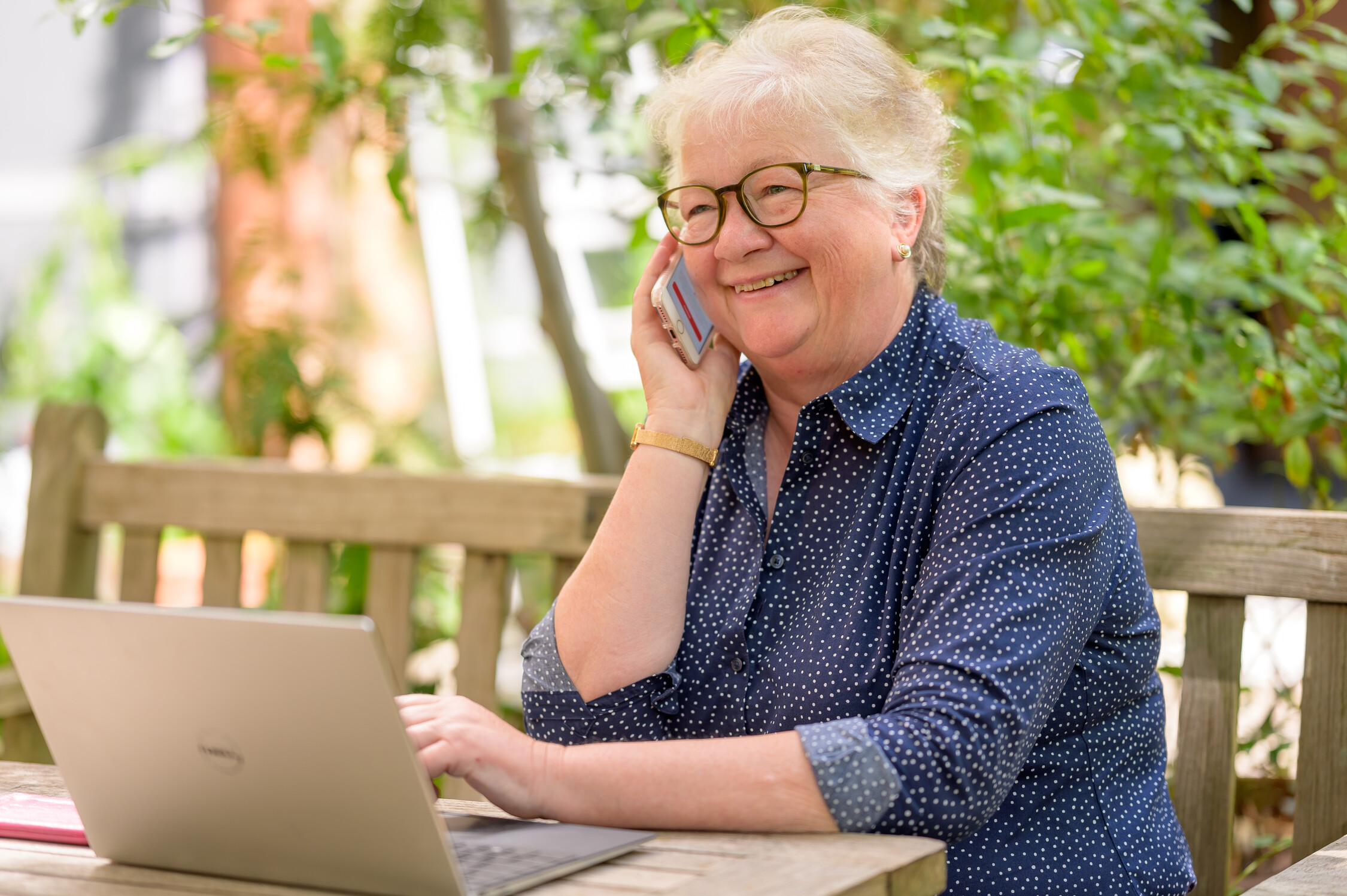 white female in front of laptop talking on cell phone