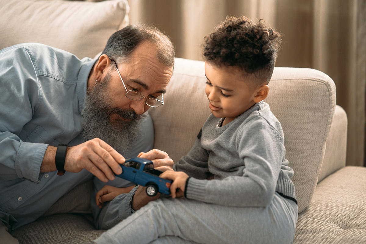 Older man and small boy examining toy truck