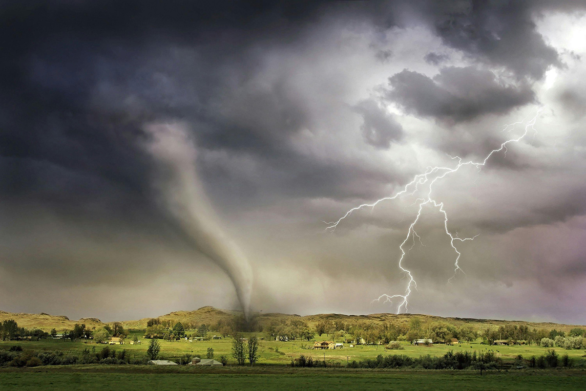 Lighting and tornado in sky above rural setting