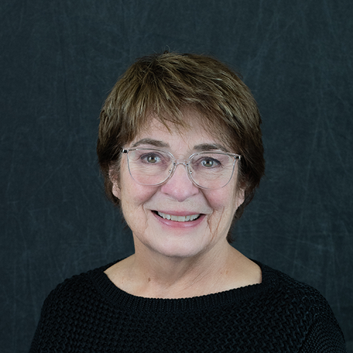 Older adult female with short brown hair and clear frame glasses