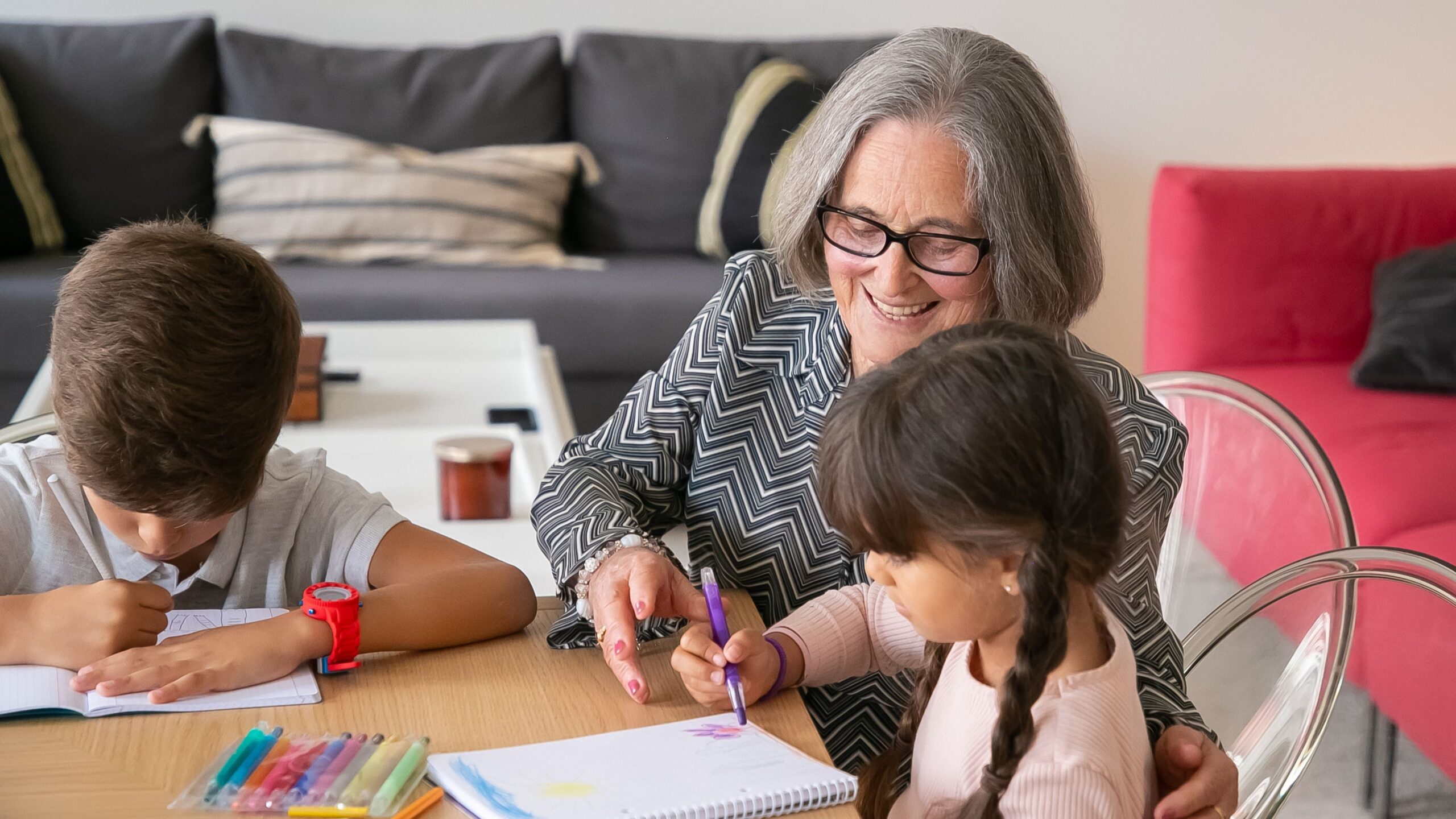 a Grandmother assisting a grandchild with a project at the table
