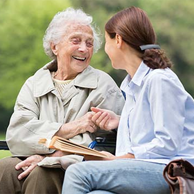 One older and one younger women sitting outside having a conversation.